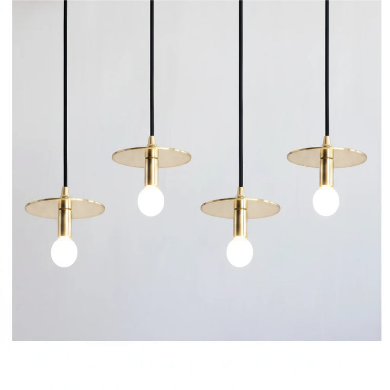 Lysverden moderne messingskivependler med synlige pærer, hengende på rad for minimalistisk spisestuebelysning.