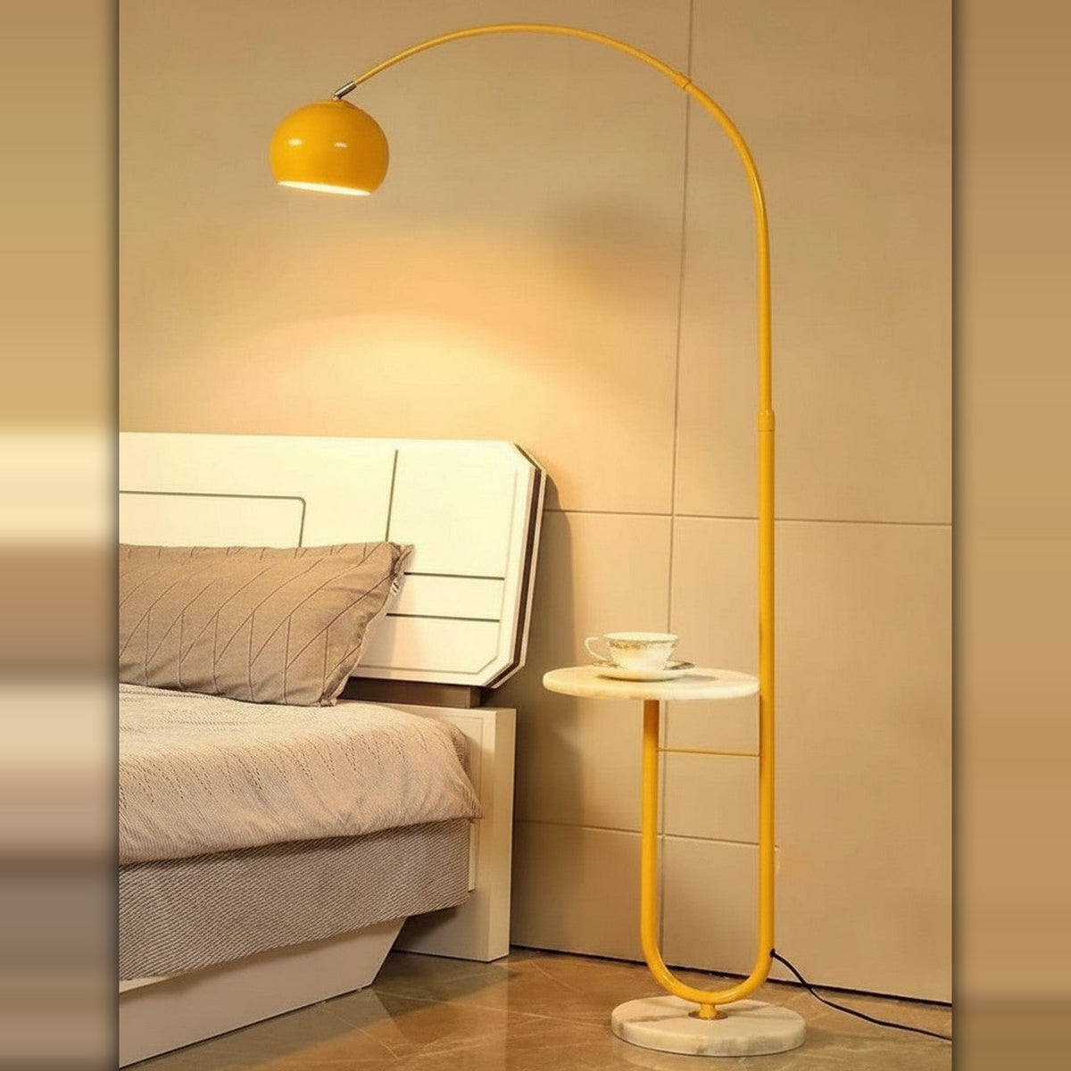 Lysverden gul buegulvlampe med steinfot og integrert sidebord ved siden av en seng i et moderne soverom.
