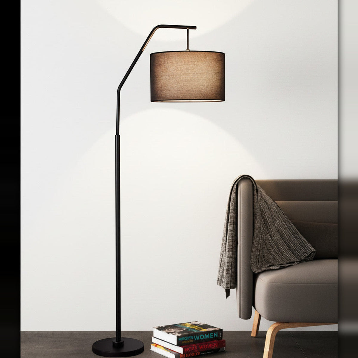 Lysverden black arc floor lamp with a fabric shade casting a warm glow over a modern sofa and a stack of books.