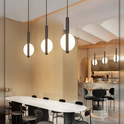 Lysverden minimalist LED pendant lights with glowing circular rings on black stems hanging over a modern dining table.
