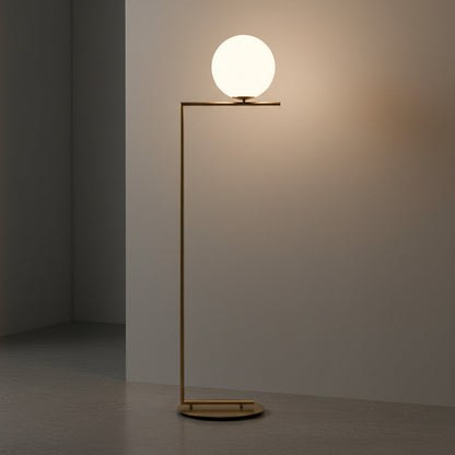 Lysverden gullfarget gulvlampe med lysende kuleskjerm i opalglass og minimalistisk metallramme i moderne interiør.