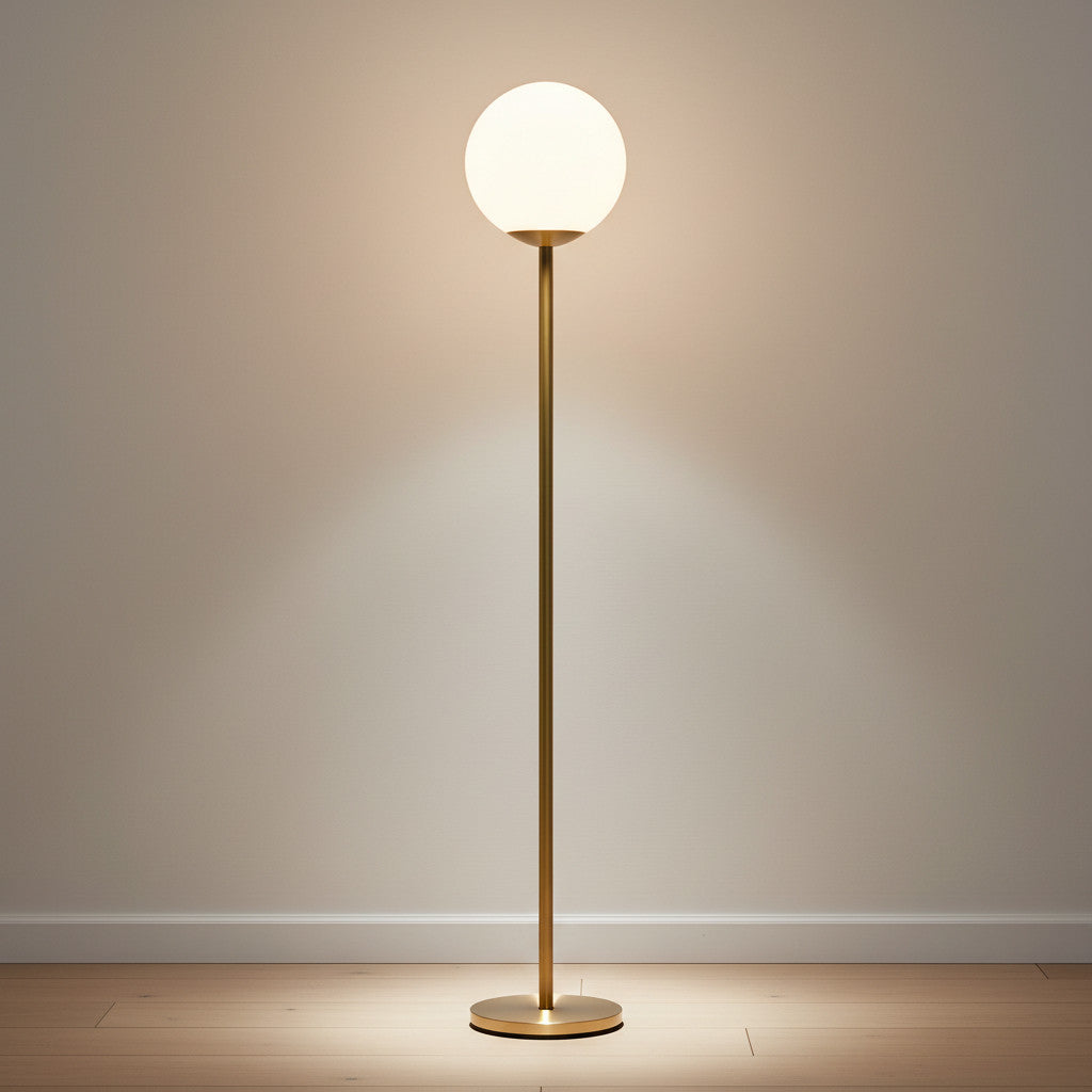 Lysverden minimalistisk gulvlampe med gullfarget metallstamme og lysende kule i opalglass som gir varmt stemningslys.