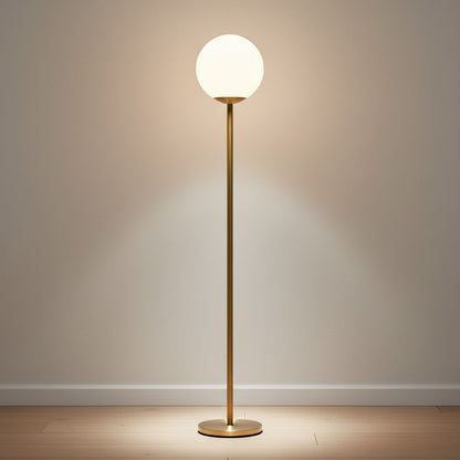 Lysverden minimalistisk gulvlampe med gullfarget metallstamme og lysende kule i opalglass som gir varmt stemningslys.