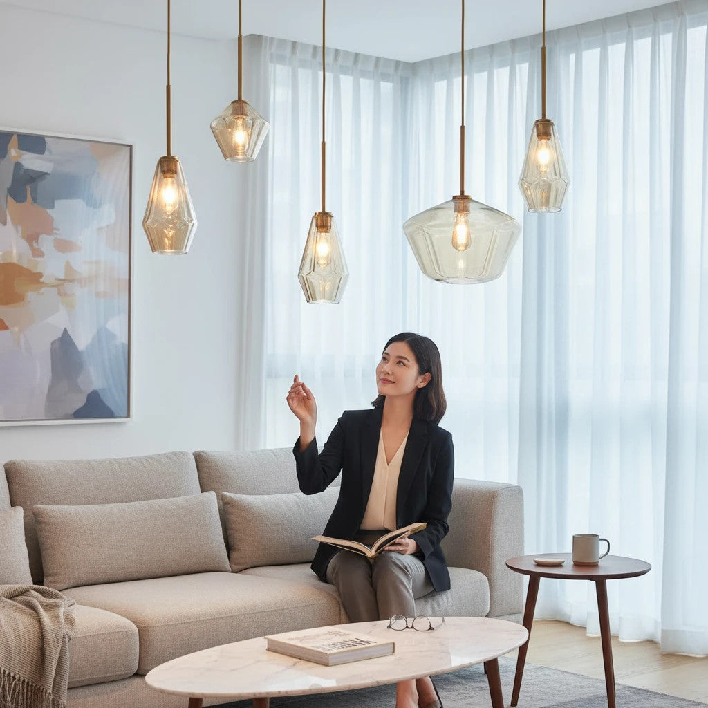 Lysverden pendellamper i ravfarget glass med messingbeslag i en moderne stue med en kvinne i sofaen