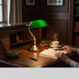 Lysverden classic banker lamp with green glass shade and bronze base, adjustable arm, and pull chain switch.