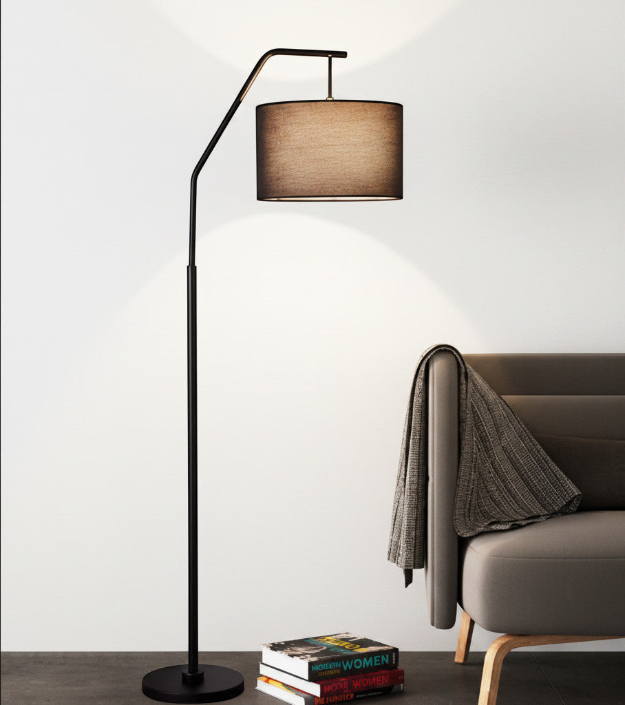 Lysverden black arc floor lamp with a fabric shade casting a warm glow over a modern sofa and a stack of books.