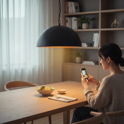 Lysverden black metal dome pendant light with a warm gold interior hanging over a wooden dining table