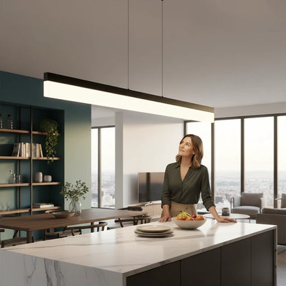 Lysverden minimalist black linear LED pendant light hanging over a modern kitchen island with a woman standing nearby.