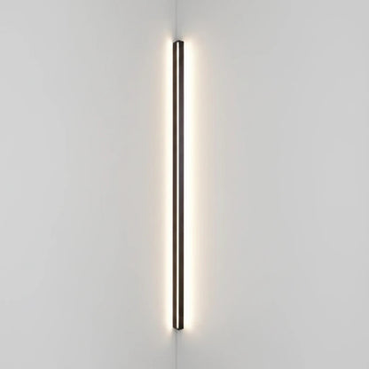 Lysverden minimalist black linear LED wall lamp mounted vertically in a corner providing warm ambient light