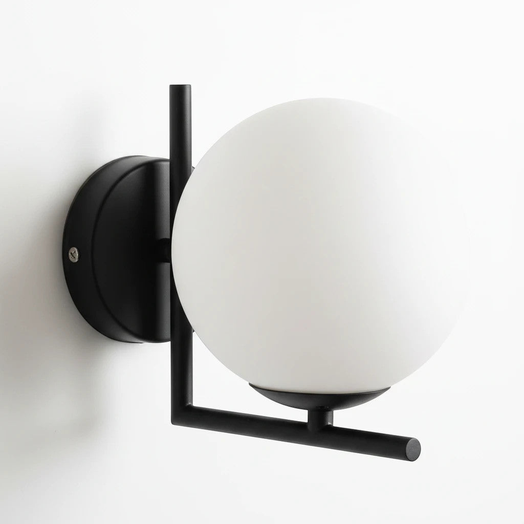 Lysverden modern wall lamp with a round opal glass globe and a minimalist black iron frame on a white wall.
