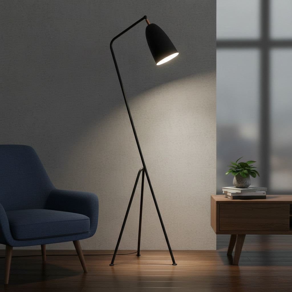 Lysverden sort gulvlampe med trebein og vippbar kjegleskjerm i en moderne stue med blå lenestol.