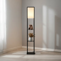 Lysverden floor lamp with black wooden frame, fabric shade, and three shelves for storage in a minimalist room.