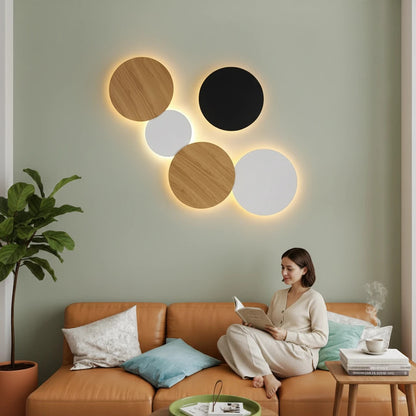 Lysverden Bobler iron wall lamp set with warm LED glow in black, white, and wood finish above a modern sofa.