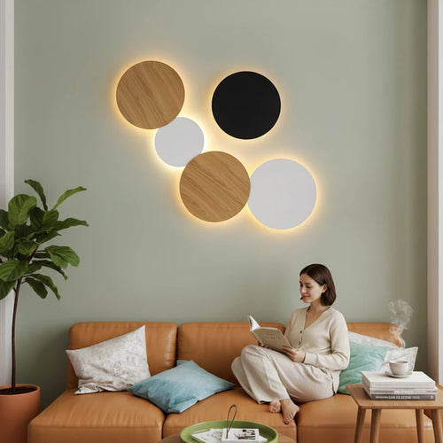 Lysverden Bobler iron wall lamp set with warm LED glow in black, white, and wood finish above a modern sofa.