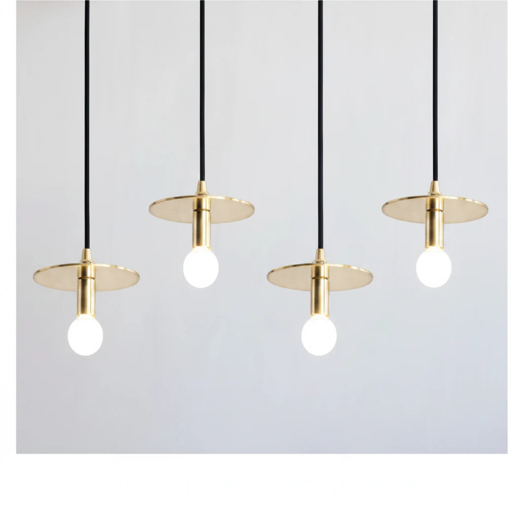 Lysverden moderne messingskivependler med synlige pærer, hengende på rad for minimalistisk spisestuebelysning.