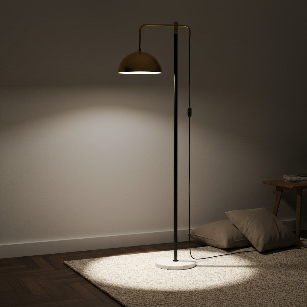 Lysverden elegant floor lamp with a polished brass dome shade on a slim black stem and white marble base in a room.