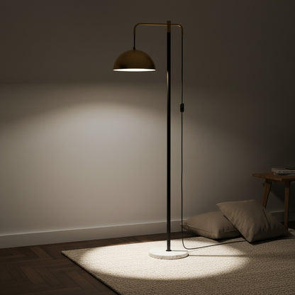Lysverden elegant floor lamp with a polished brass dome shade on a slim black stem and white marble base in a room.