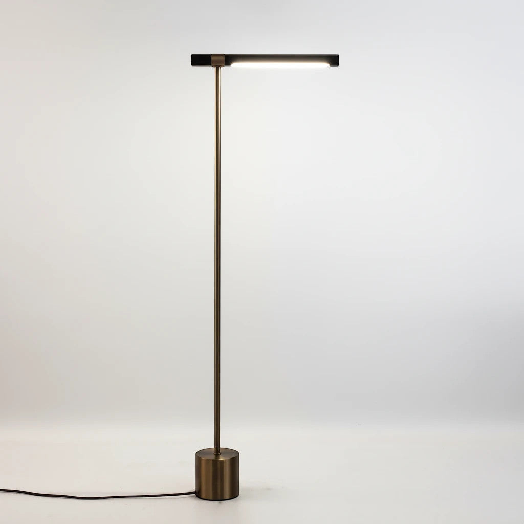 Lysverden floor lamp with a slim brass stand, cylindrical base, and integrated LED light bar in a minimalist design.