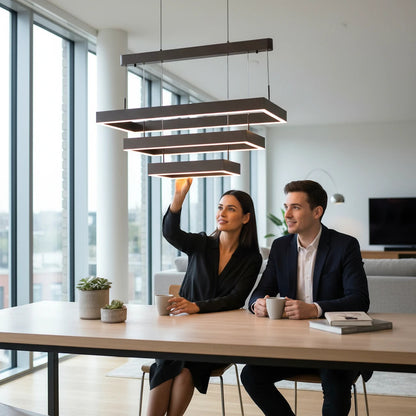 Lysverden rectangular LED chandelier with three stacked bronze frames hanging over a modern dining table with a couple.