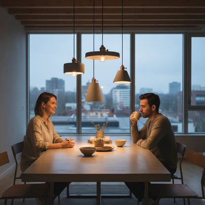 Lysverden concrete pendant lamps with brass details hanging over a dining table with a couple in a modern apartment.