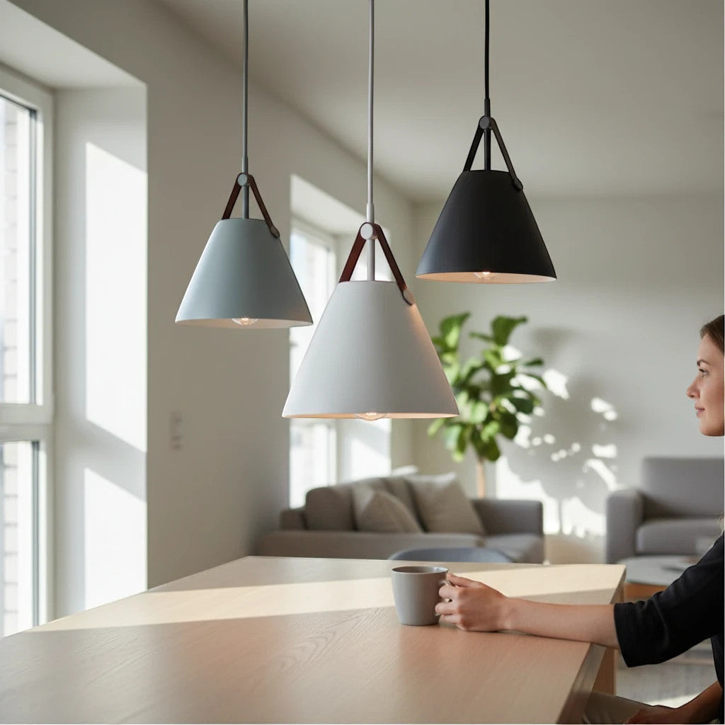Lysverden conical metal pendant lights in grey, white, and black with leather strap details hanging over a table.
