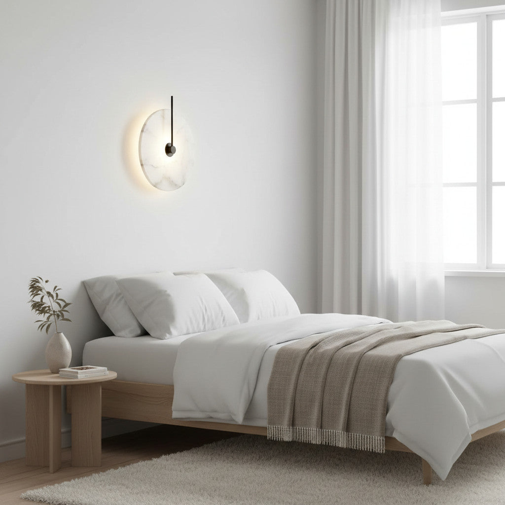 Lysverden Dolomitt wall lamp with a white stone disc and warm LED glow mounted above a minimalist bedroom bed.