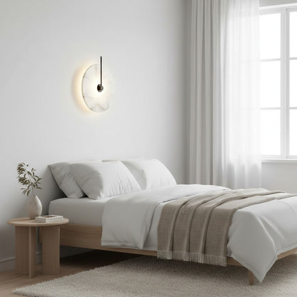 Lysverden Dolomitt wall lamp with a white stone disc and warm LED glow mounted above a minimalist bedroom bed.