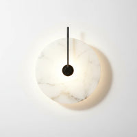 Lysverden Dolomitt minimalist wall lamp with a round white marble disc and black metal detail emitting warm LED light.