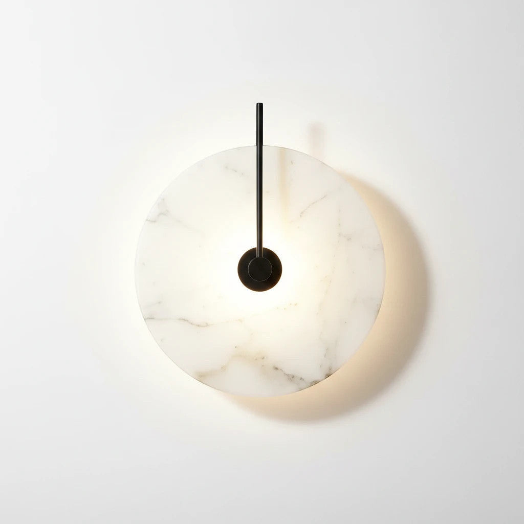 Lysverden Dolomitt minimalistisk vegglampe med rund skive i hvit marmor og sort metalldetalj som gir varmt LED-lys.