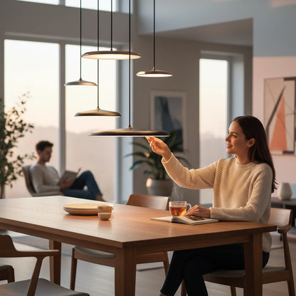 Lysverden modern flat metal LED pendant lights hanging over a wooden dining table with a woman adjusting the light