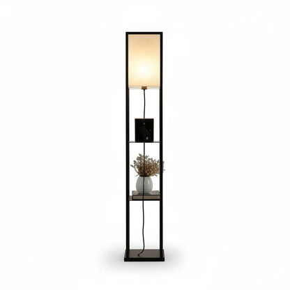Lysverden floor lamp with black wooden frame, three storage shelves, and a soft white fabric shade emitting warm light.