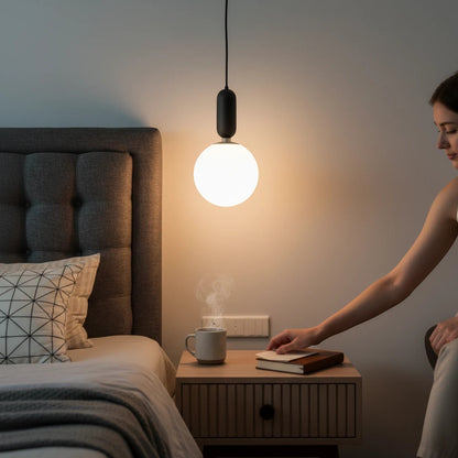 Lysverden GLOBE pendant lamp with opal glass sphere and black fixture, providing soft warm light in a modern bedroom.