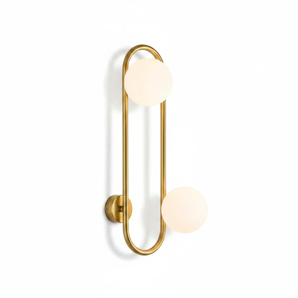 Lysverden midt-century wall lamp with a gold brass ring and two white glass globes emitting a soft warm light.
