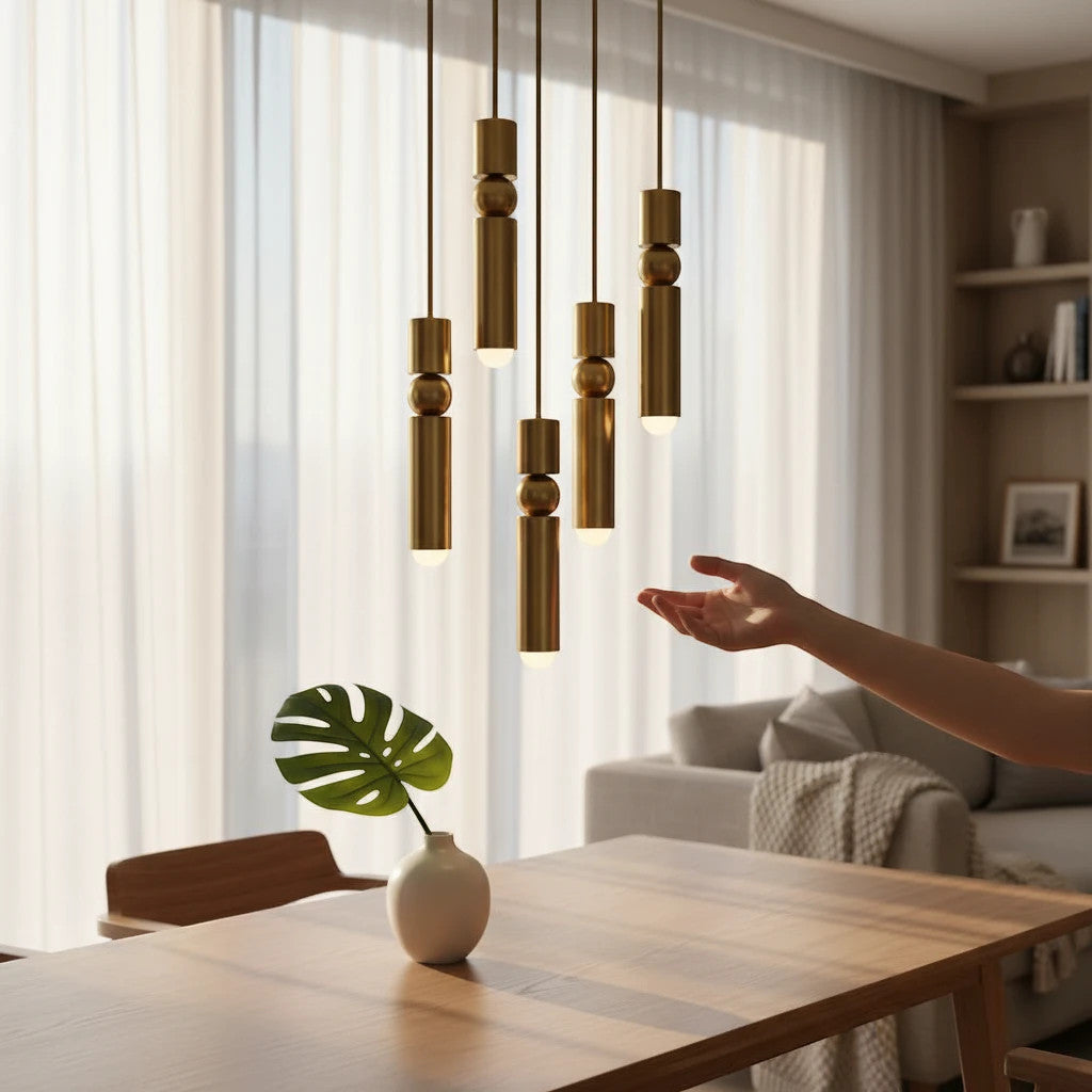 Lysverden gold cylinder pendant lights with spherical details hanging in a cluster over a wooden dining table.