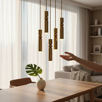 Lysverden gold cylinder pendant lights with spherical details hanging in a cluster over a wooden dining table.
