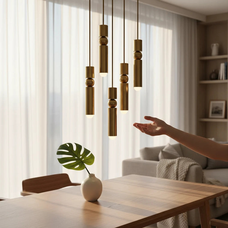 Lysverden gold cylinder pendant lights with spherical details hanging in a cluster over a wooden dining table.