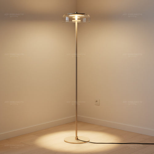 Lysverden elegant floor lamp in gold with a clear glass disk shade casting a warm glow in a minimalist room corner.