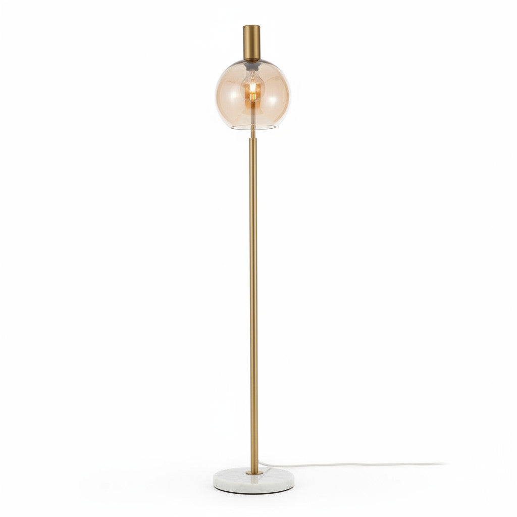 Lysverden floor lamp with a gold metal stem, amber glass globe shade, and a circular white marble base.