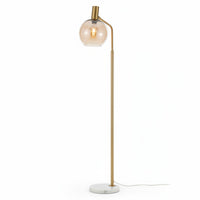 Lysverden floor lamp with a gold metal stem, amber glass globe shade, and a circular white marble base.