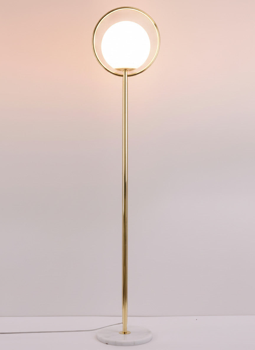Lysverden gold floor lamp with a circular metal frame and a white opal glass sphere on a marble base.