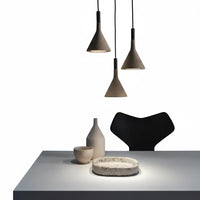Lysverden grey concrete conical pendant lights hanging over a minimalist dining table with ceramic decor