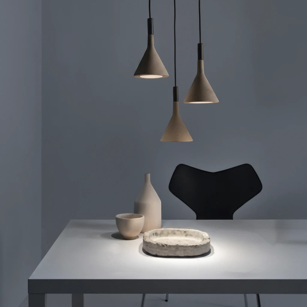 Lysverden grey concrete pendant lights with slim conical design hanging over a modern dining table