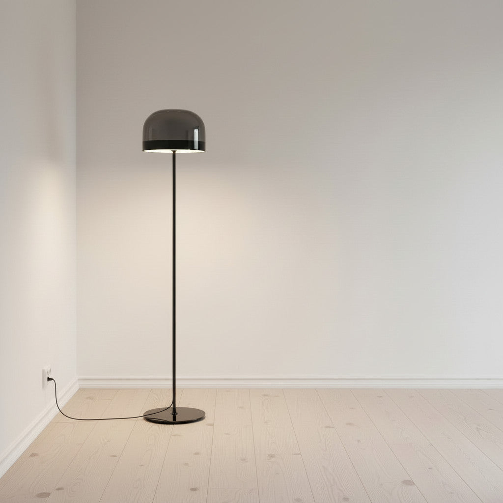 Lysverden floor lamp with a grey smoked glass dome and slim black stand, creating a soft glow in a minimalist room.