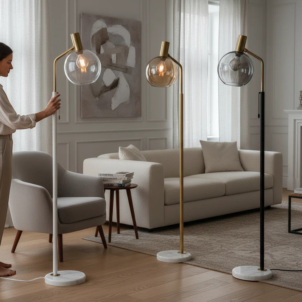 Lysverden floor lamps with marble bases and glass globes in white, gold, and black standing in a modern living room.