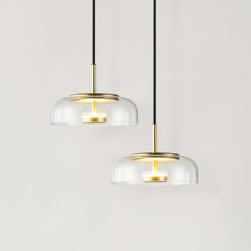 Lysverden KUPPEL pendant lights with clear glass domes and polished brass reflectors hanging on black cords.
