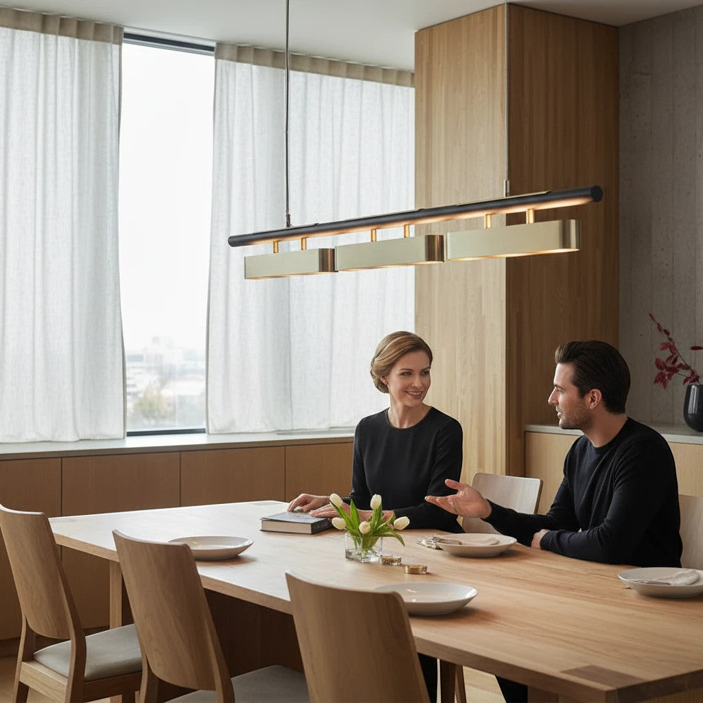 Lysverden linear wood and brushed brass LED pendant light hanging over a modern dining table with a couple sitting