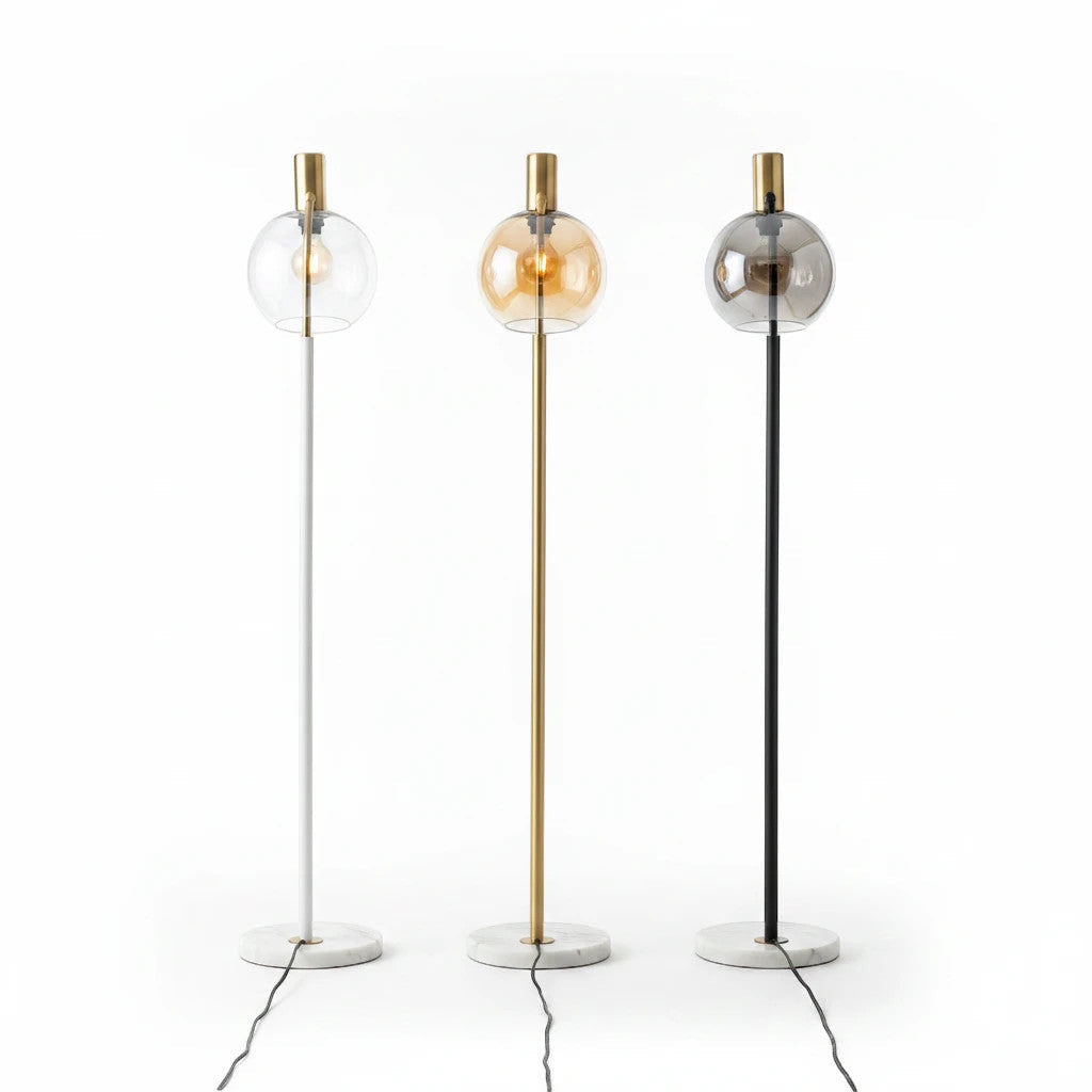 Lysverden floor lamps with marble bases, glass globes, and white, gold, and black metal stems in a minimalist style.