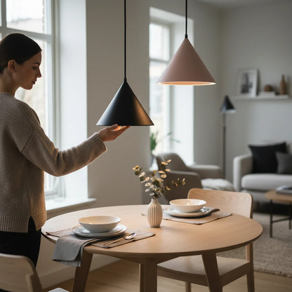 Lysverden matte black and pink conical pendant lights hanging over a wooden dining table in a modern Nordic interior.