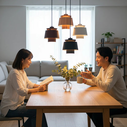 Lysverden metal drum pendant lights in black, gold, and white hanging over a dining table with a couple sitting.