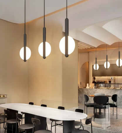 Lysverden minimalist LED pendant lights with glowing circular rings on black stems hanging over a modern dining table.